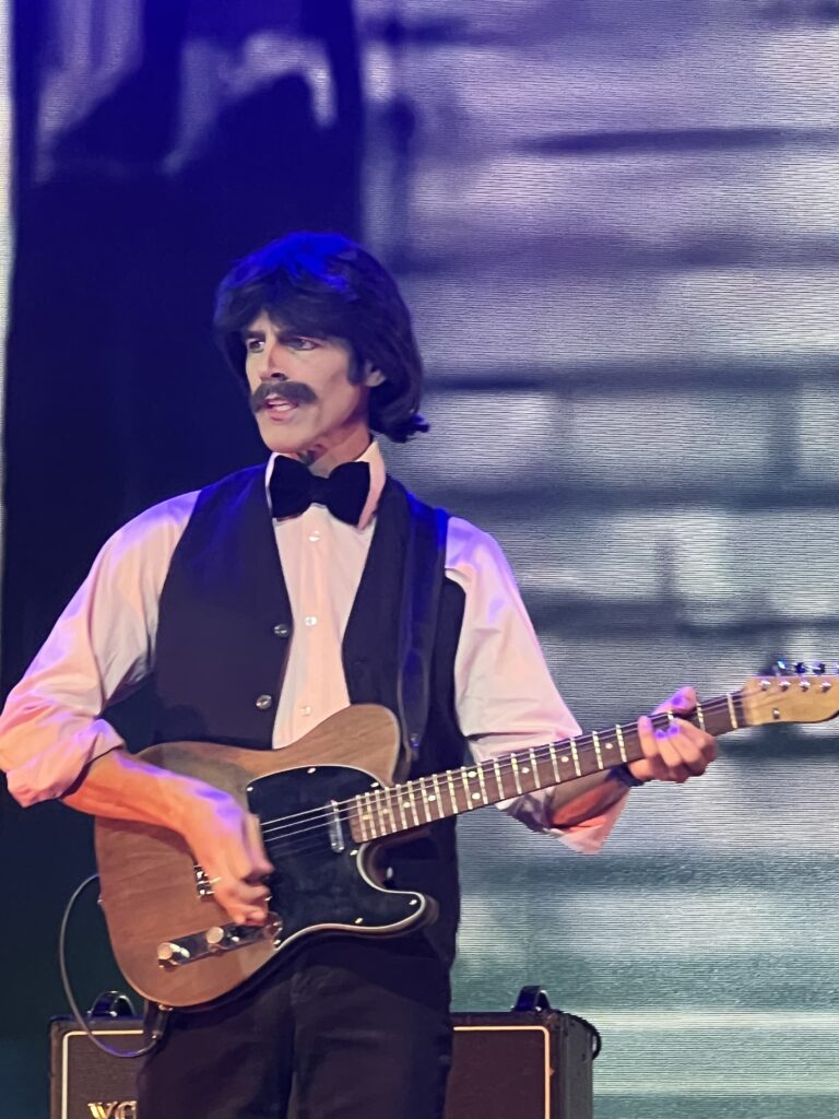 George, wearing pink shirt and black waistcoat and playing the Rosewood Telecaster during Get Back