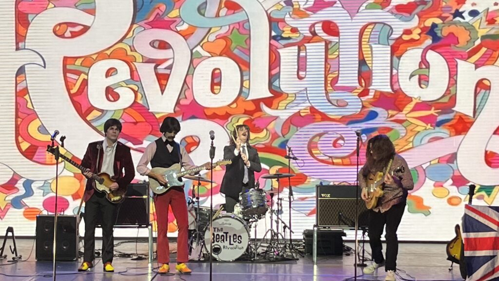 The Liverpool Beatles performing their centrepiece Beatles Revolution show with Revolution background